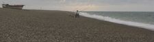 Lone fisherman on shingle beach